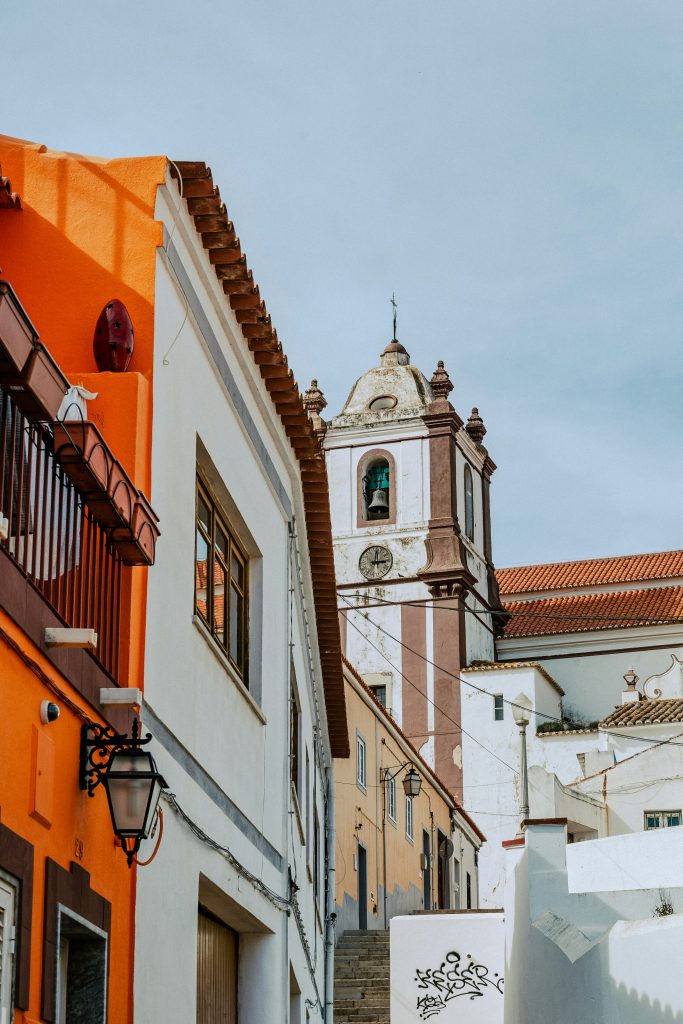 A brightly coloured wall and a church tower in Silves, Portugal